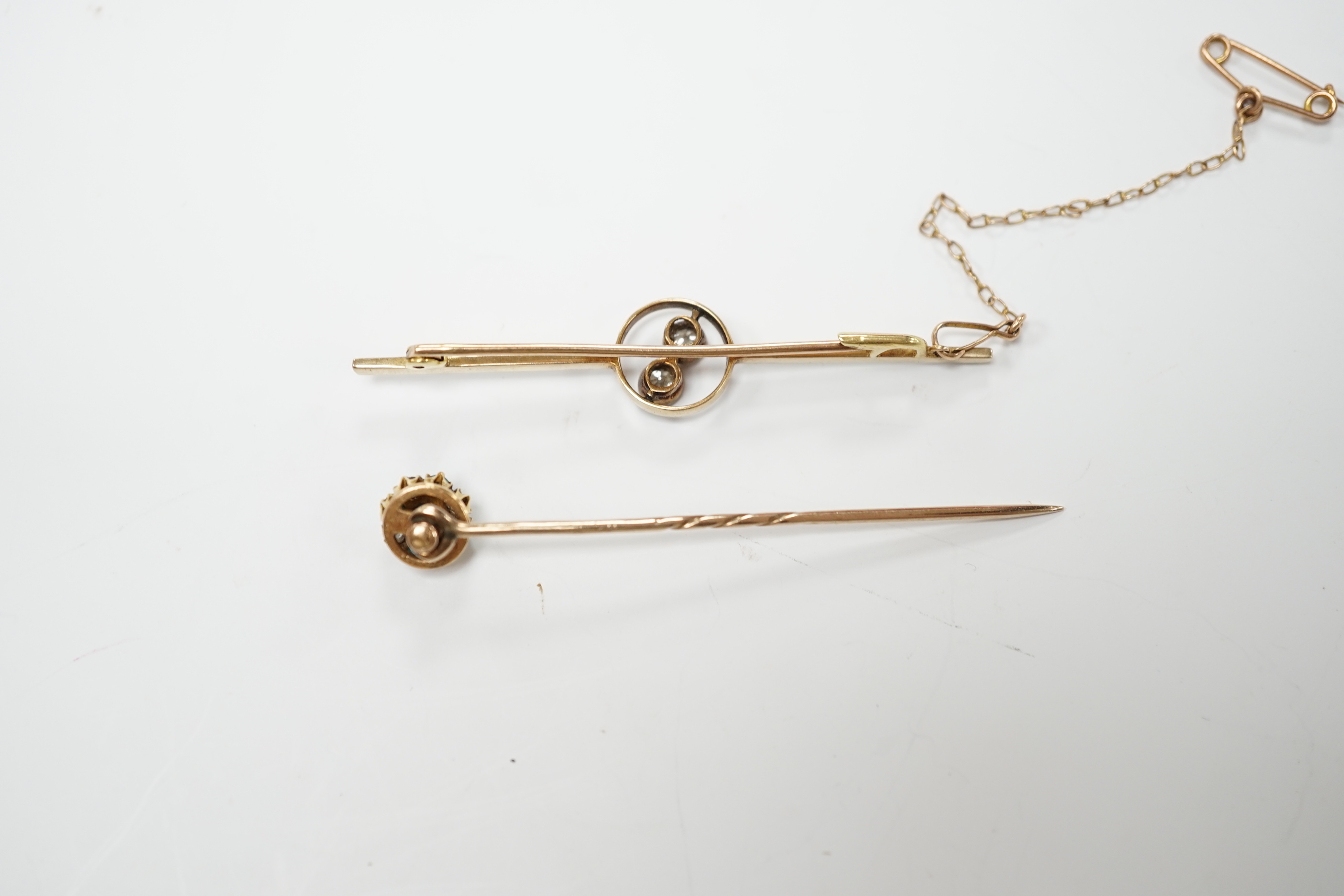 An early 20th century yellow metal, white metal and two stone diamond crossover set bar brooch, 57mm and a similar turquoise and diamond cluster set stick pin.